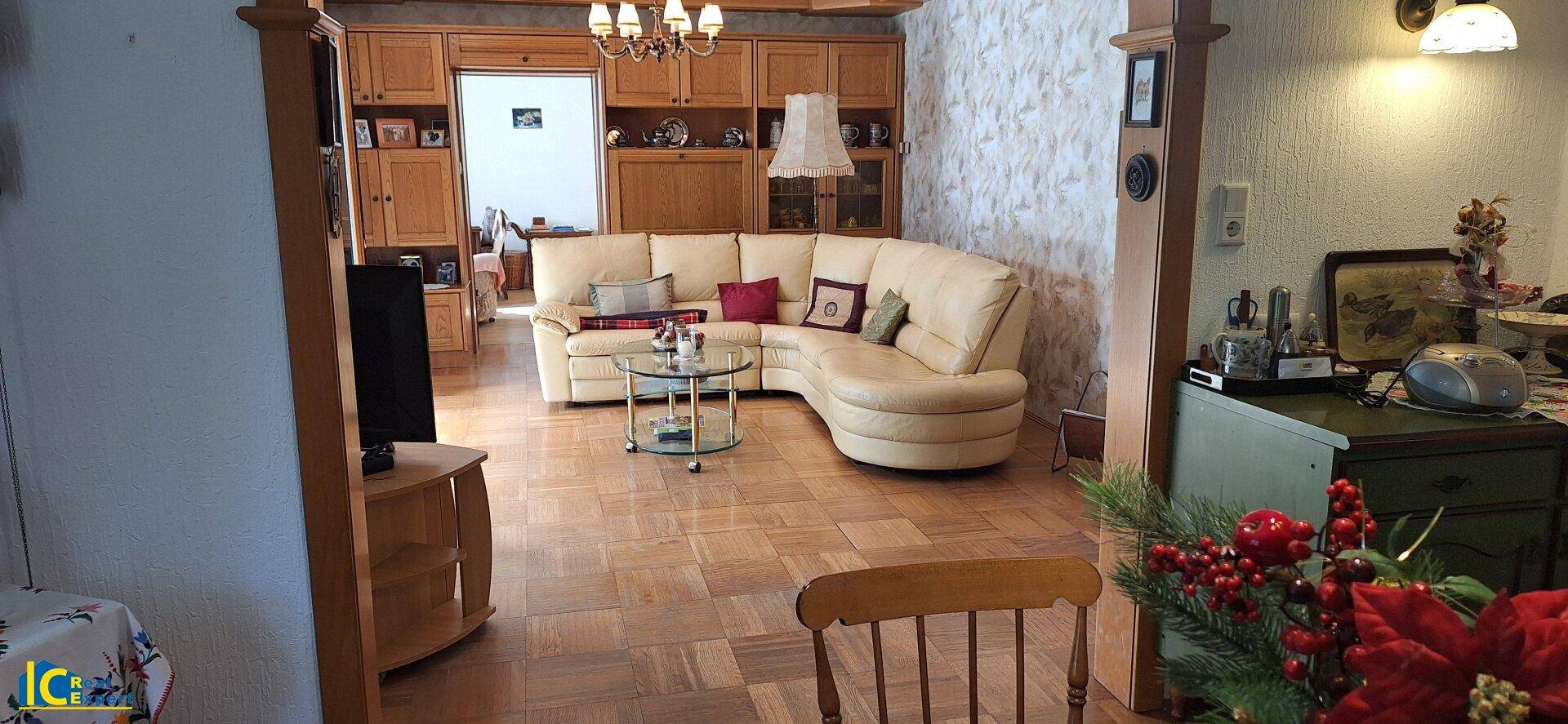 Gemütliches Wohnzimmer mit Ecksofa, Holzmöbeln und Parkettboden in traditionellem Stil.