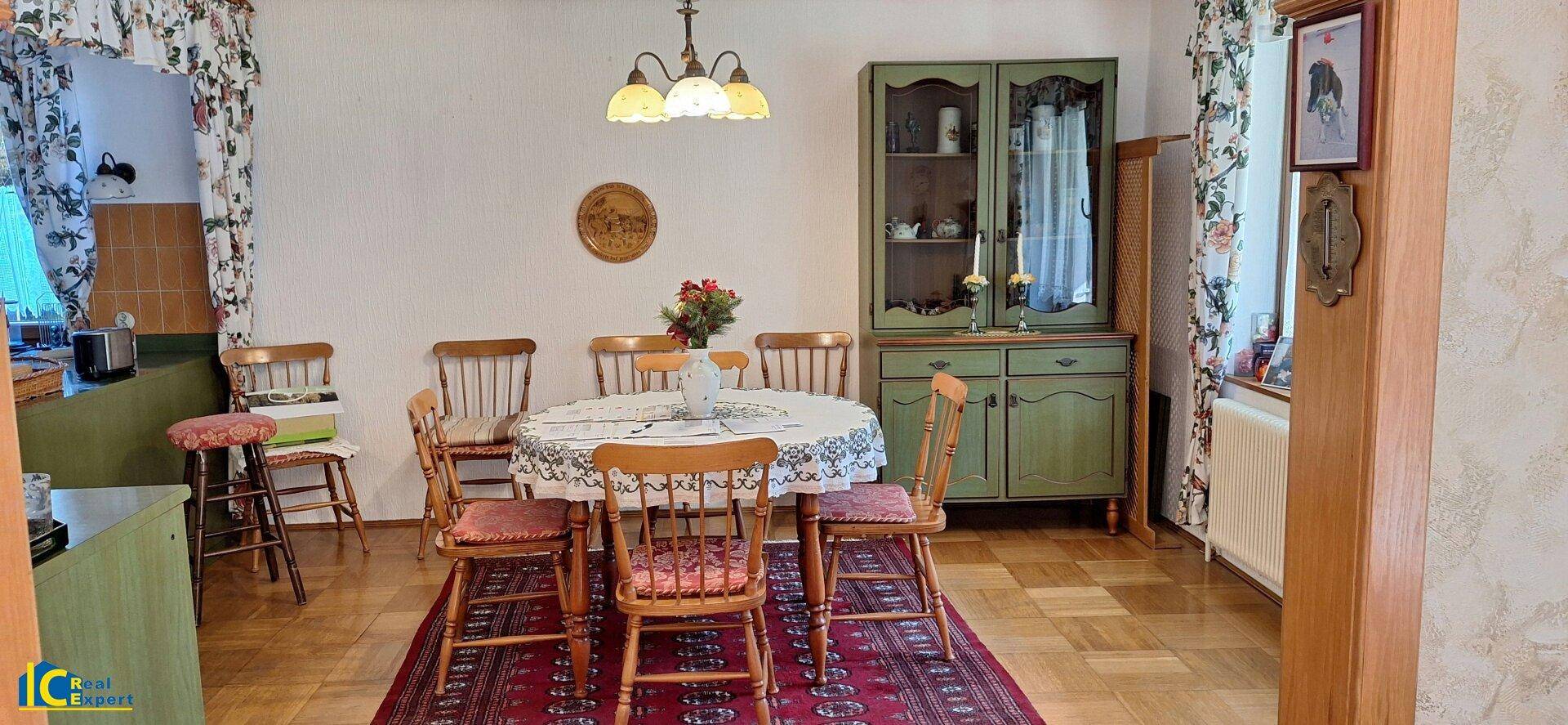 Essbereich mit rustikalen Holzstühlen, Esstisch und grünem Schrank in traditionellem Ambiente.