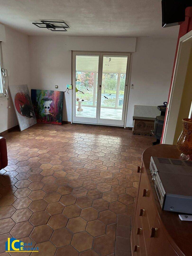 Wohnzimmer mit sechseckigen Terrakottafliesen und Zugang zu einem verglasten Außenbereich.