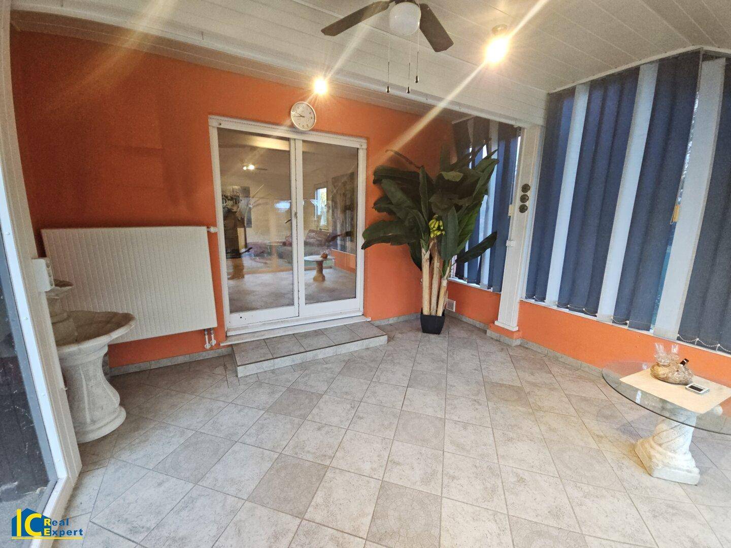 Geräumiger Wintergarten mit Fliesenboden, Deckenventilator und Zugang zum Wohnbereich.