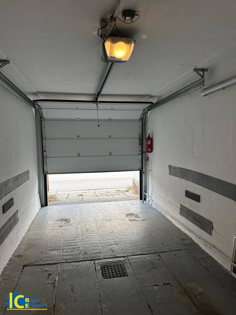 Geräumige Garage mit Betonboden und offenem Rolltor, bereit für Fahrzeuge oder Lagerung.