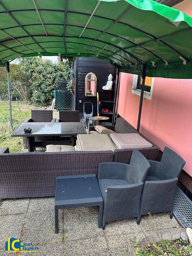 Überdachte Terrasse mit Outdoor-Sitzgruppe und Blick auf den Gartenbereich.