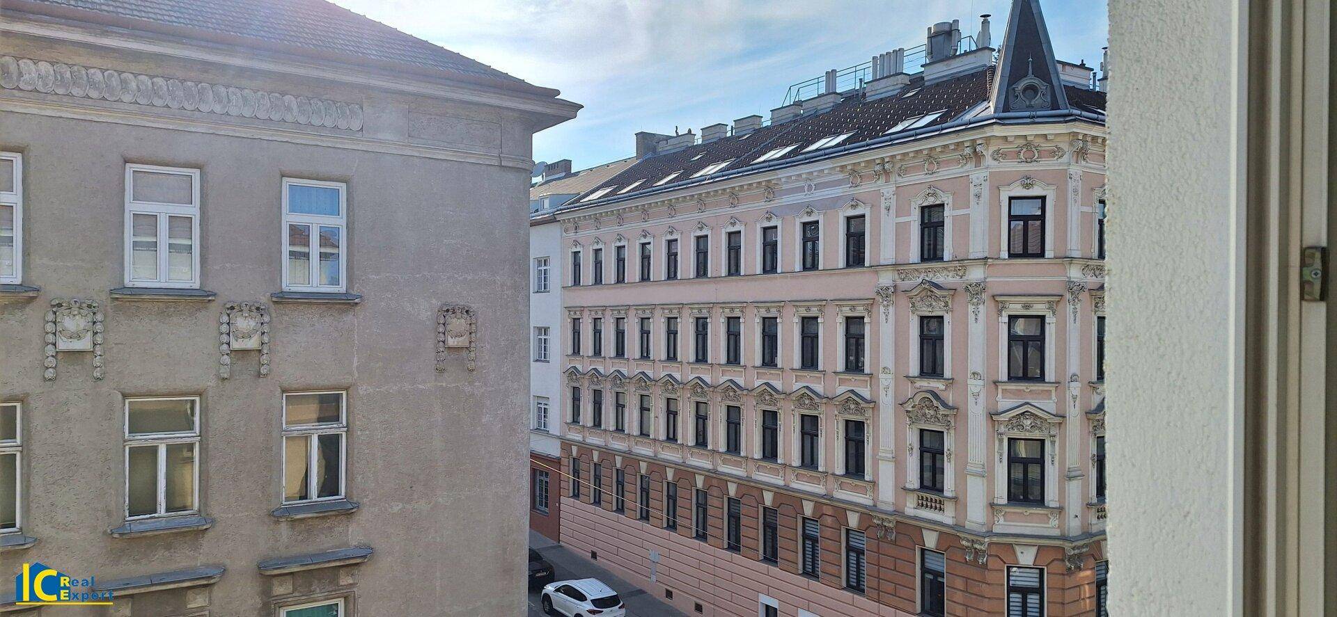 Blick aus dem Fenster auf zwei historische Gebäude mit detailreichen Fassaden und einer ruhigen Straße.