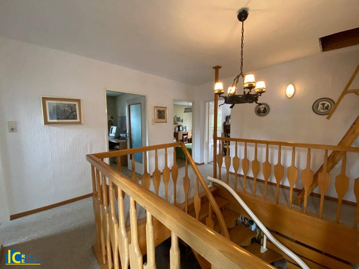 Heller Treppenabsatz mit Holzgeländer und Blick in den unteren Bereich des Hauses.