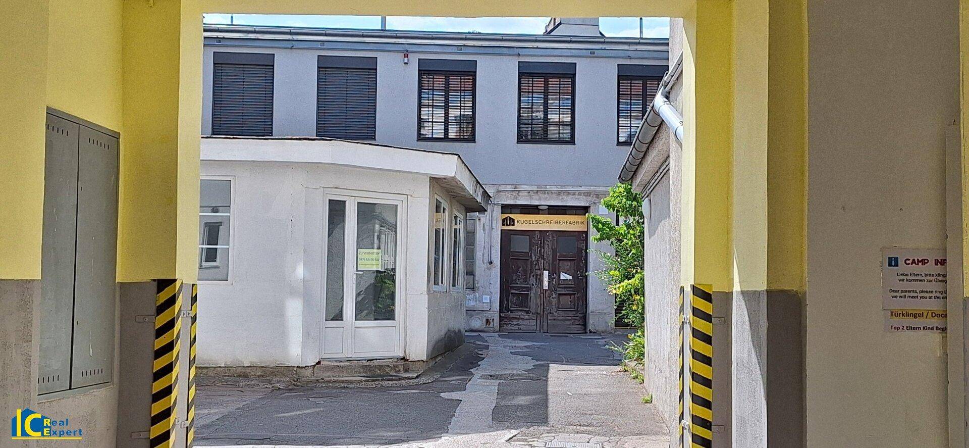 Nahaufnahme des Blicks durch den Torbogen in den Innenhof mit dem kleinen Gebäude und weiteren Gebäuden.