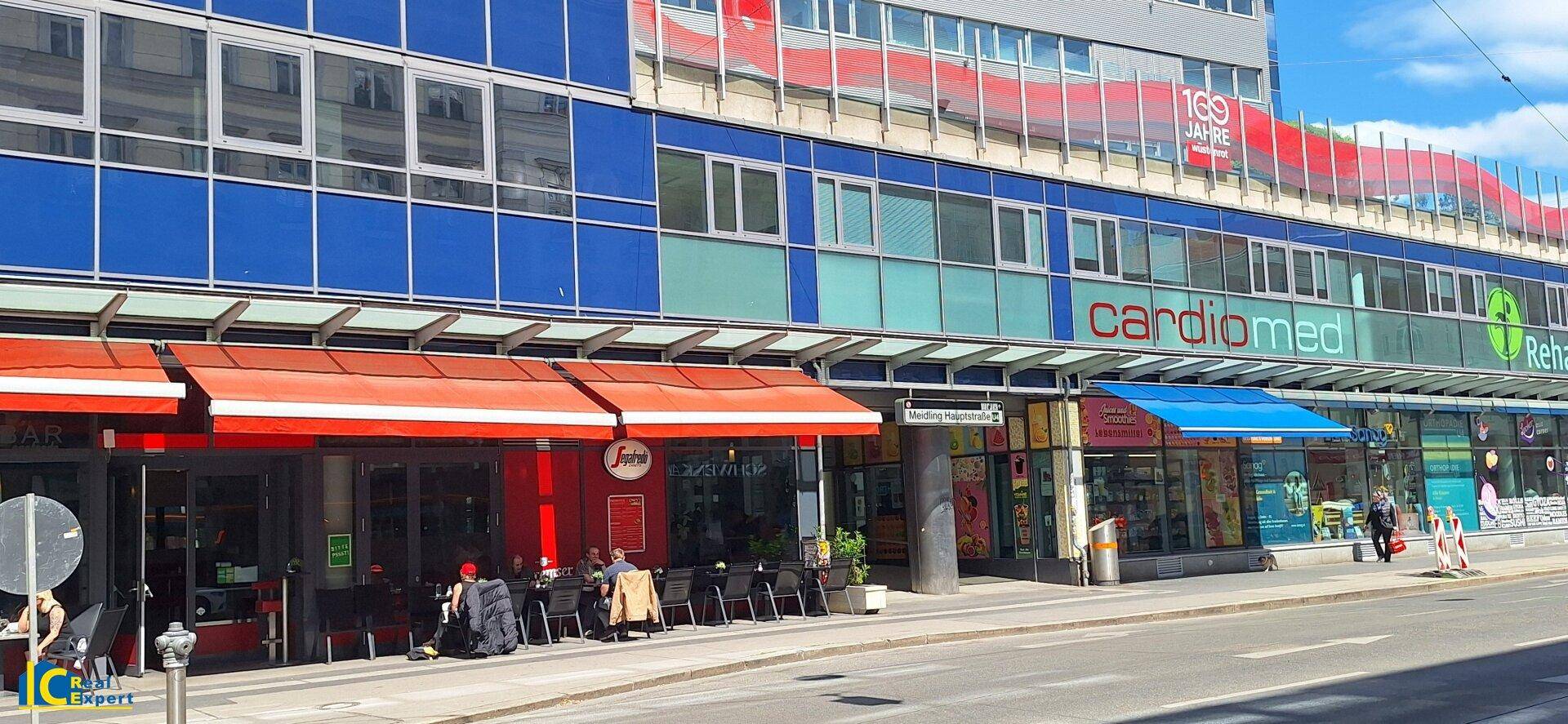Geschäftige Straße mit verschiedenen Geschäften, Restaurants und Außensitzplätzen.