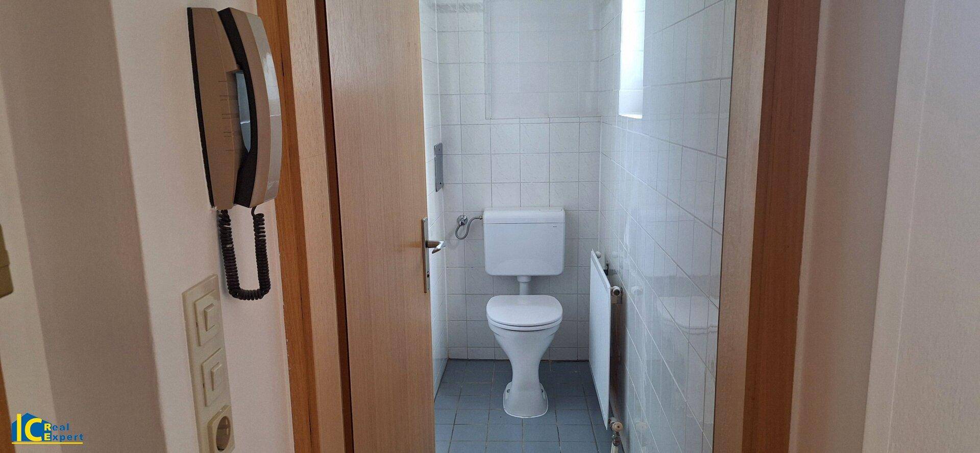 Separates WC mit Toilette und hellen Wandfliesen.