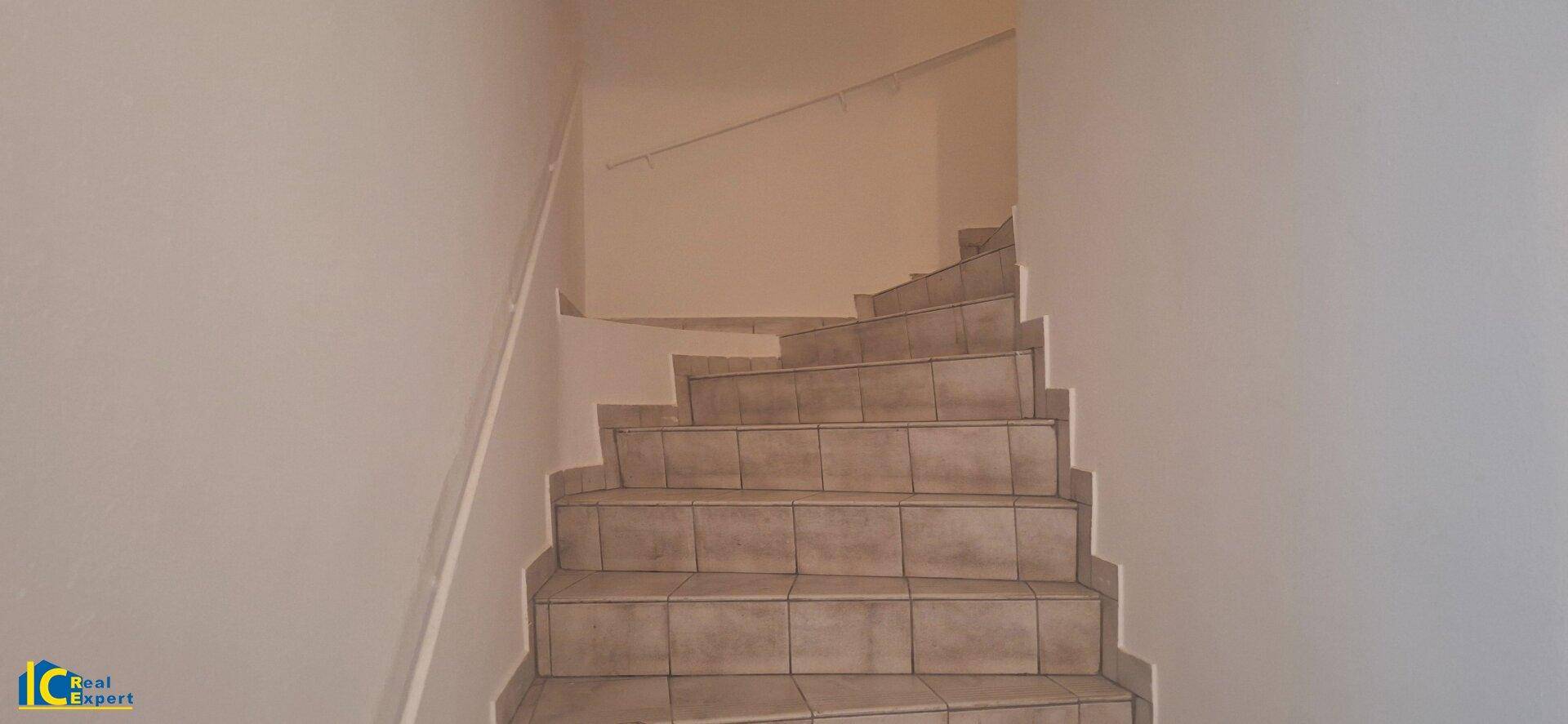 Treppenhaus mit gefliesten Stufen und hellem Anstrich.
