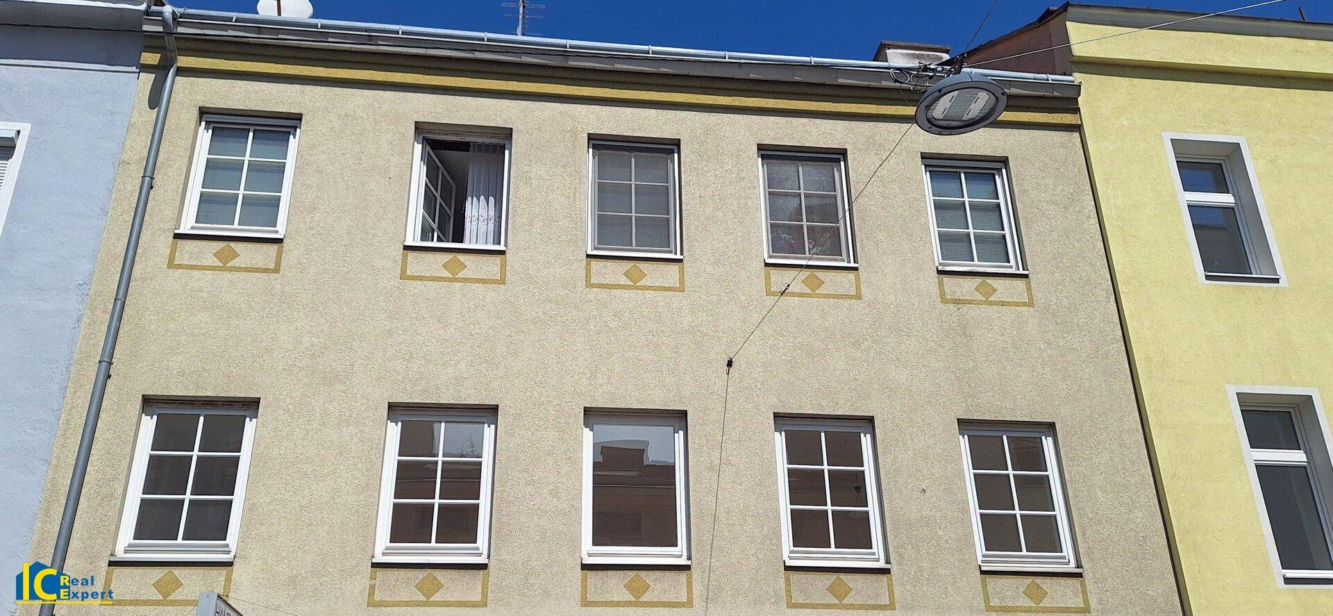 Fassade eines älteren Gebäudes mit mehreren Fenstern und einfacher Architektur.