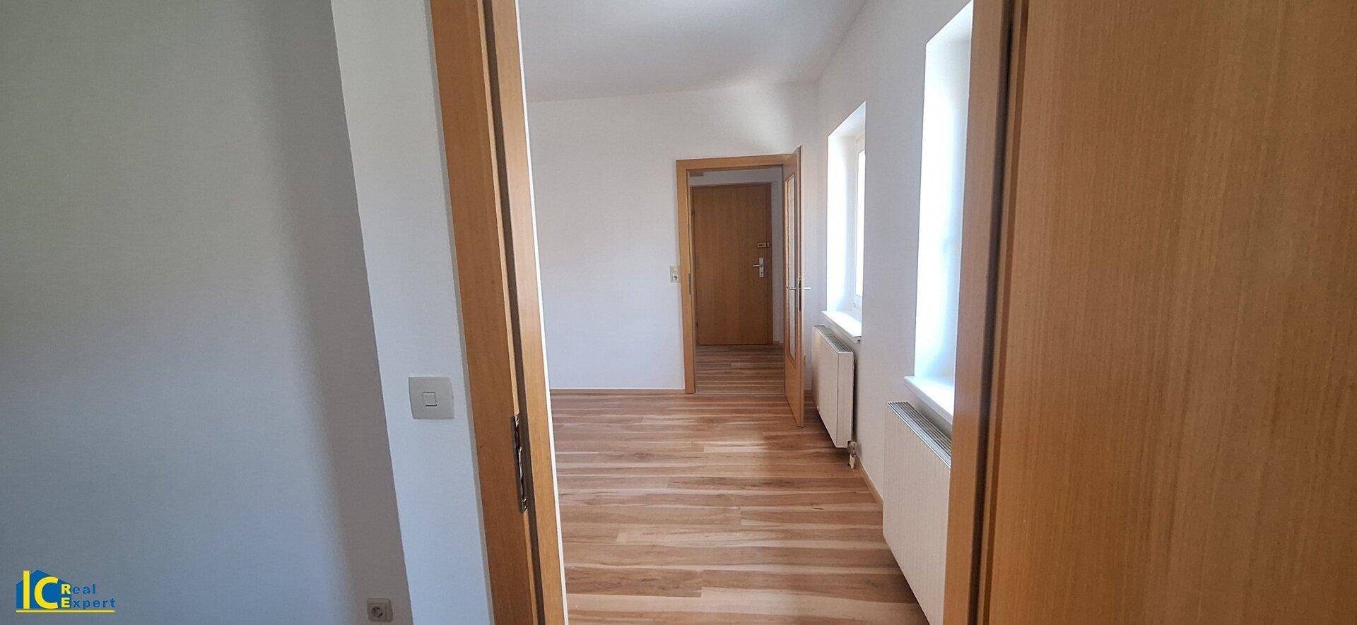 Heller Flur mit Holzboden und mehreren Türen zu angrenzenden Räumen.
