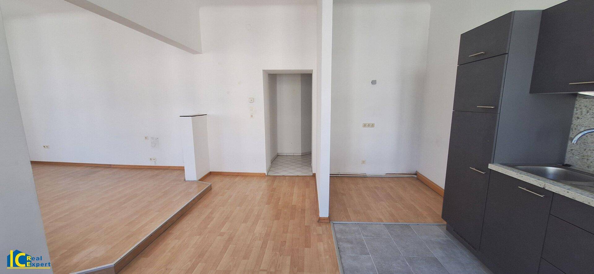 Blick von der Küche in den Wohnbereich, der durch einen leichten Höhenunterschied getrennt ist.
