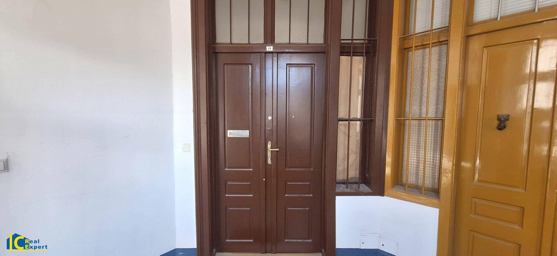 Eingangstüren eines Mehrfamilienhauses mit traditionellen Holzelementen und Oberlichtern.
