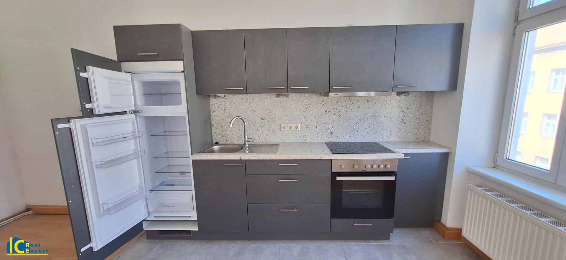 Detailansicht der modernen Einbauküche mit offenem Kühlschrank und Gefrierfach.