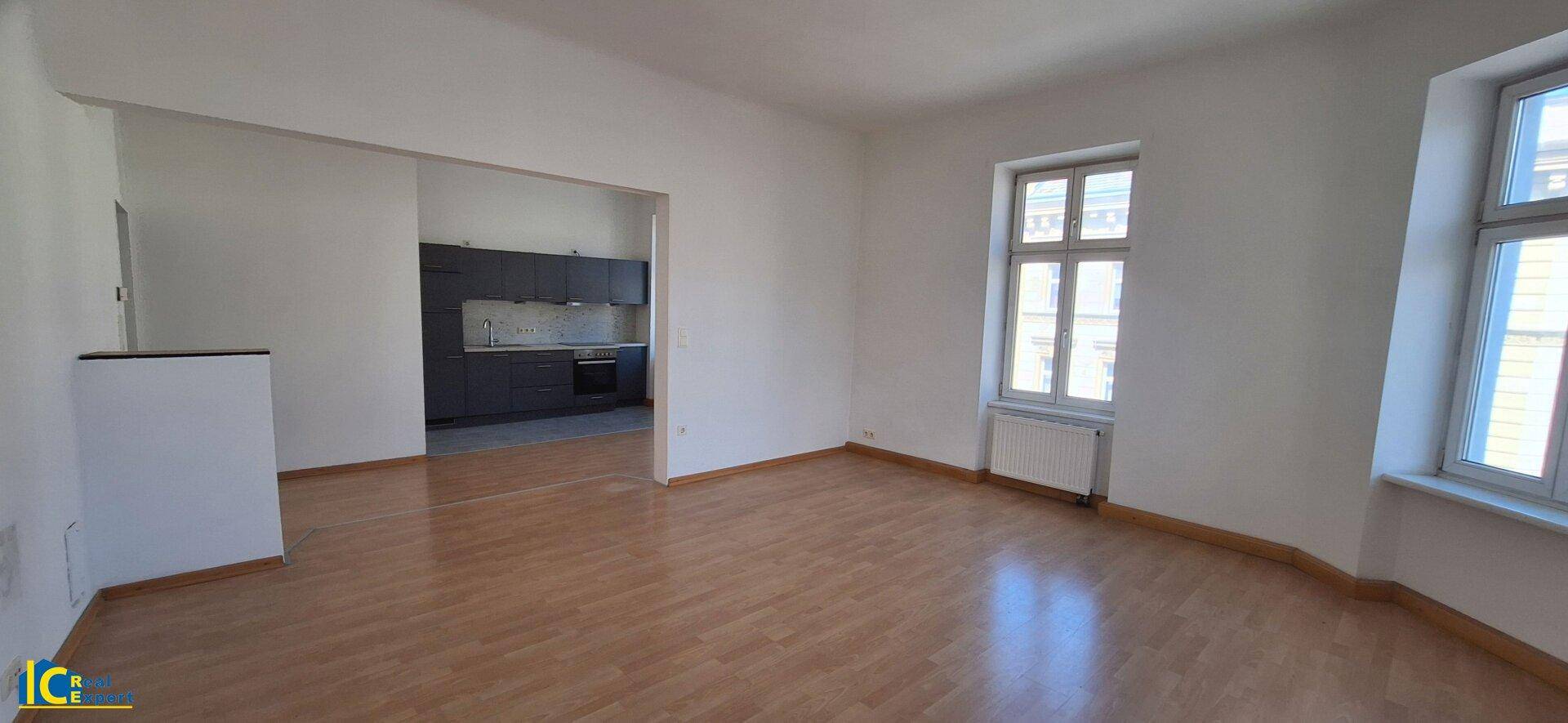 Offener Wohnbereich mit Holzfußboden und Blick auf die angrenzende moderne Küche.