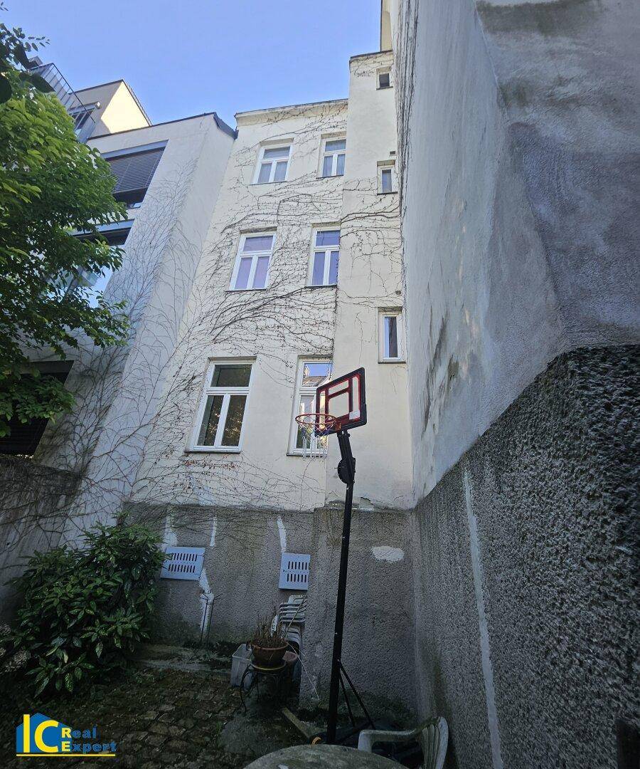 Hinterhof mit Basketballkorb und begrünten Wänden, umgeben von Gebäudefassaden, bietet Spielmöglichkeiten.
