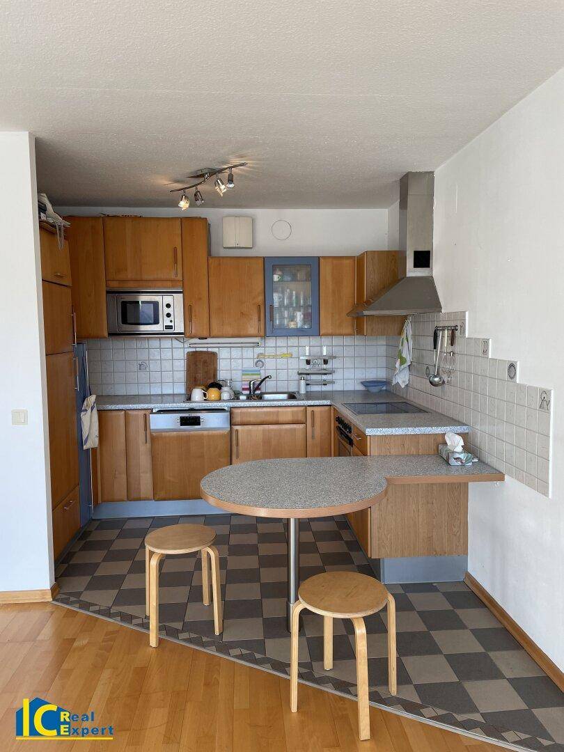 Funktionale Küche mit Holzschränken, integrierten Geräten und einem kleinen Frühstückstresen.