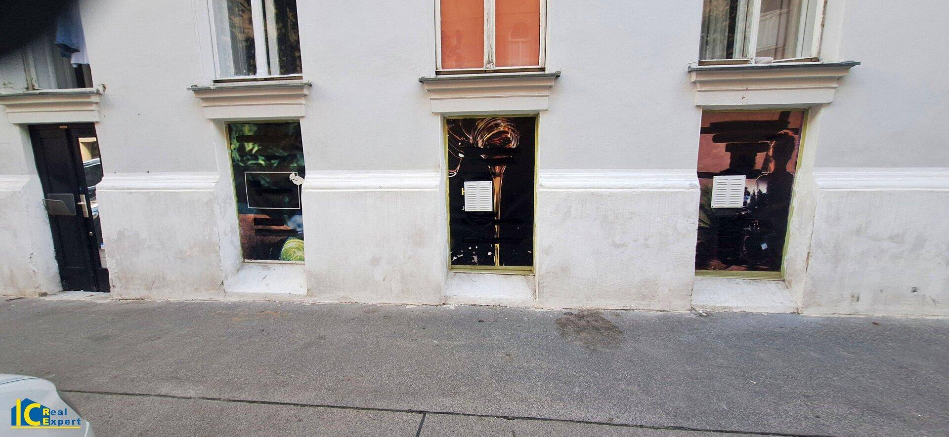 Erdgeschossfassade mit mehreren Fenstern und Eingängen, die auf eine belebte Straße blicken.