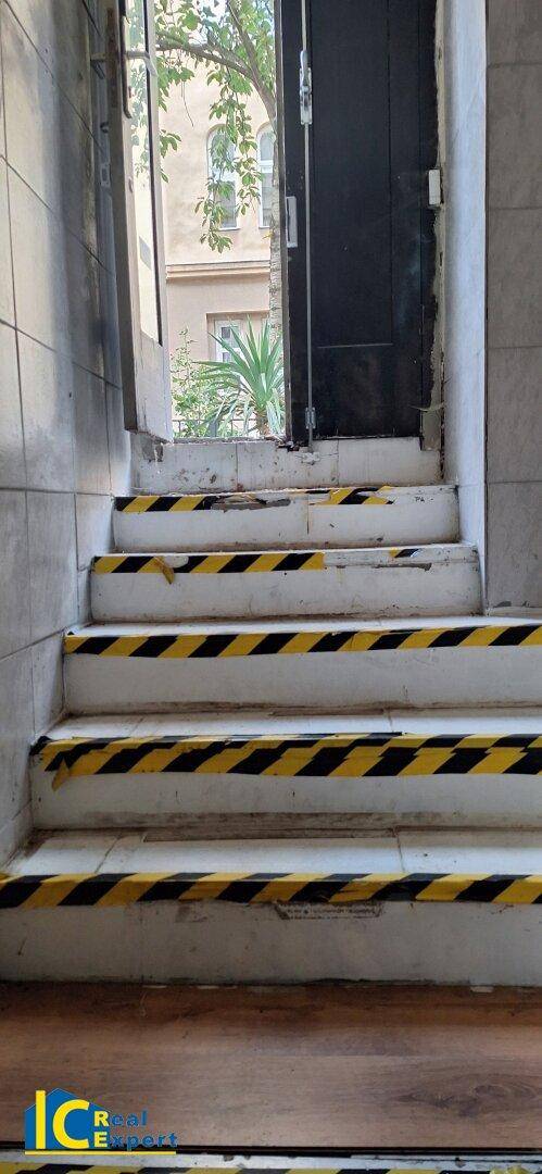 Eingangsbereich mit Treppe, die mit gelb-schwarzem Warnband markiert ist, führt ins Freie.