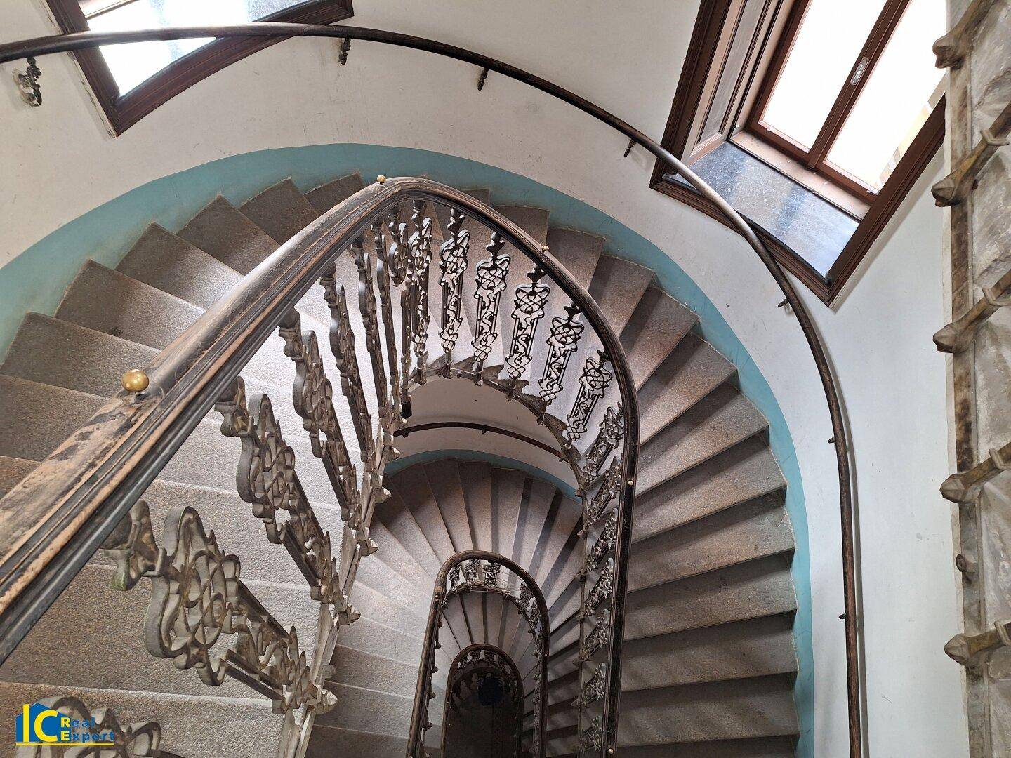 Elegante Wendeltreppe mit kunstvollem Geländer und Oberlicht, das natürliches Licht spendet.