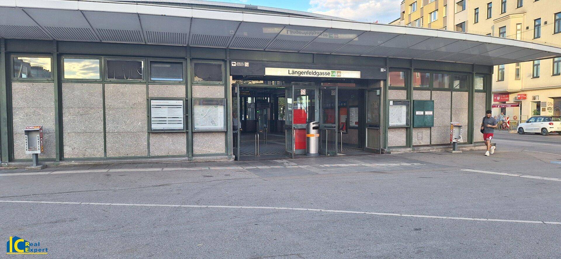 Eingang zur U-Bahn-Station Längenfeldgasse mit Glasfassade und Passanten auf dem Gehweg.