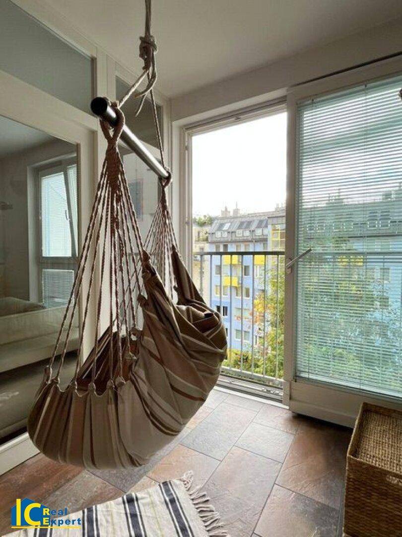 Gemütlicher Balkon mit Hängesessel und Fliesenboden, ideal zum Entspannen im Freien.