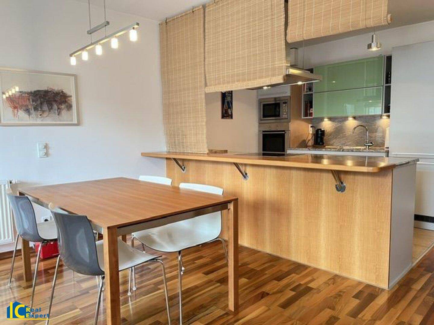 Moderne Küche mit Holzarbeitsplatte, integrierten Geräten und Essbereich am Tresen.
