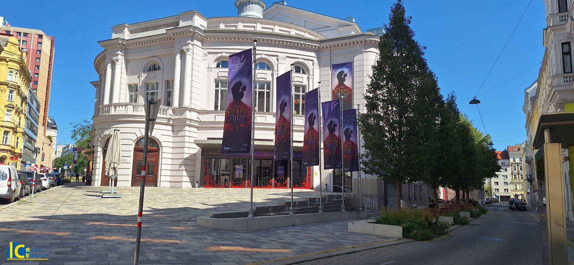 Eindrucksvolles klassisches Gebäude mit weißer Fassade und Fahnen vor dem Eingangsbereich.