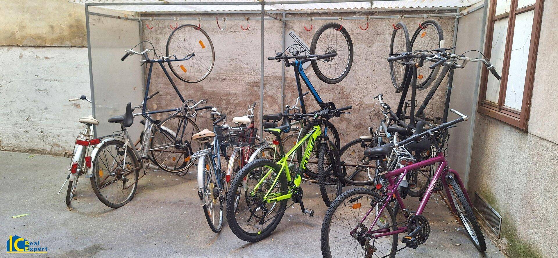 Überdachter Fahrradabstellplatz mit mehreren Fahrrädern und einem einfachen Unterstand.