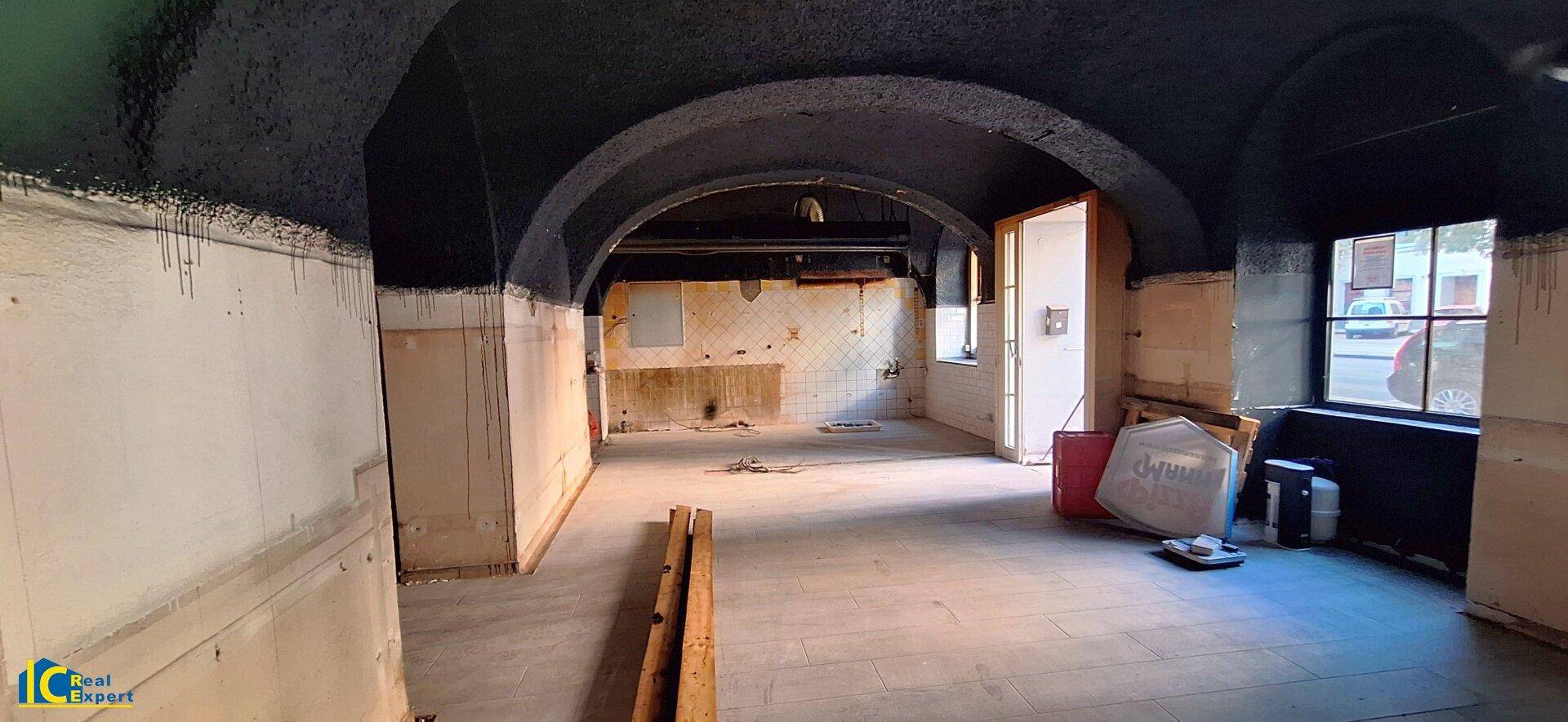 Innenraum mit gewölbter Decke, dunkler Farbe und sichtbaren Renovierungsspuren, mit einem Fenster.