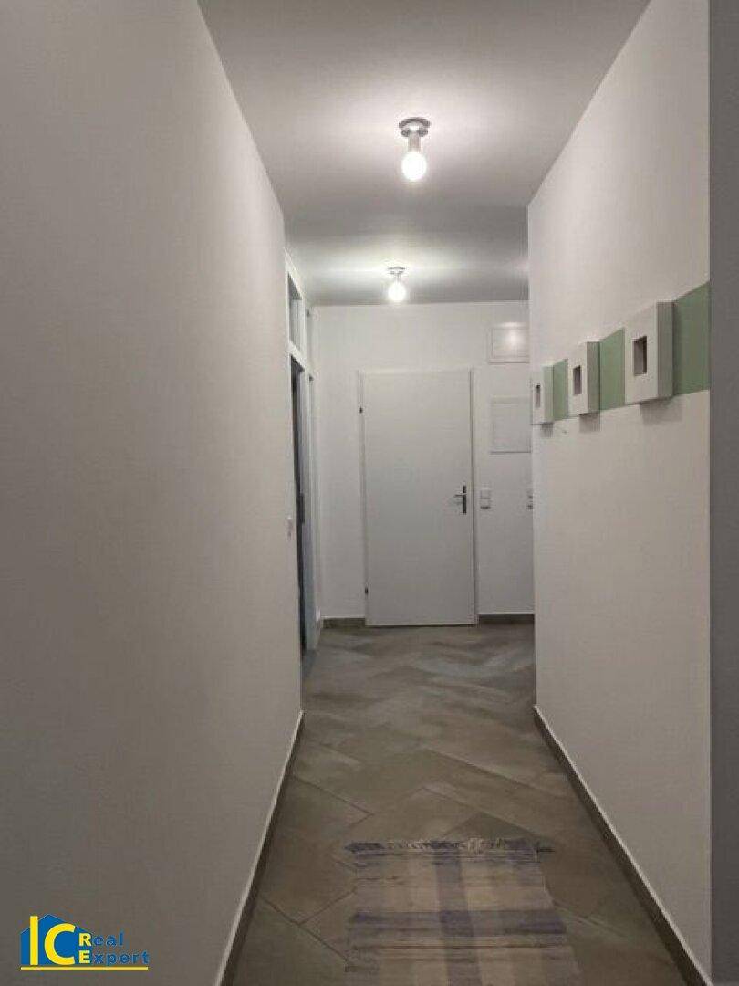 Langer Flur mit hellem Fliesenboden und schlichten weißen Wänden, der zu weiteren Räumen führt.