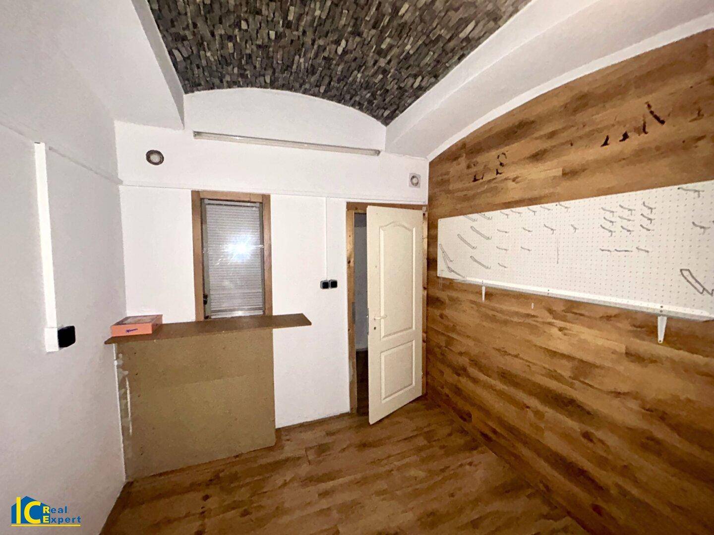 Raum mit Holzwandverkleidung, gewölbter Decke und einem kleinen Fenster.