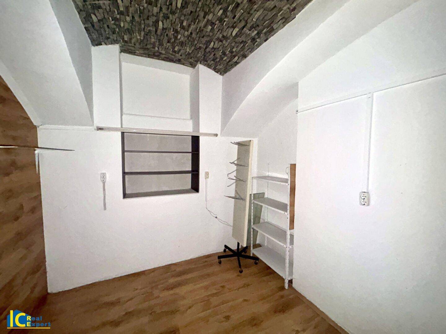 Raum mit gewölbter Decke, Regalen und einem Fenster, das natürliches Licht spendet.