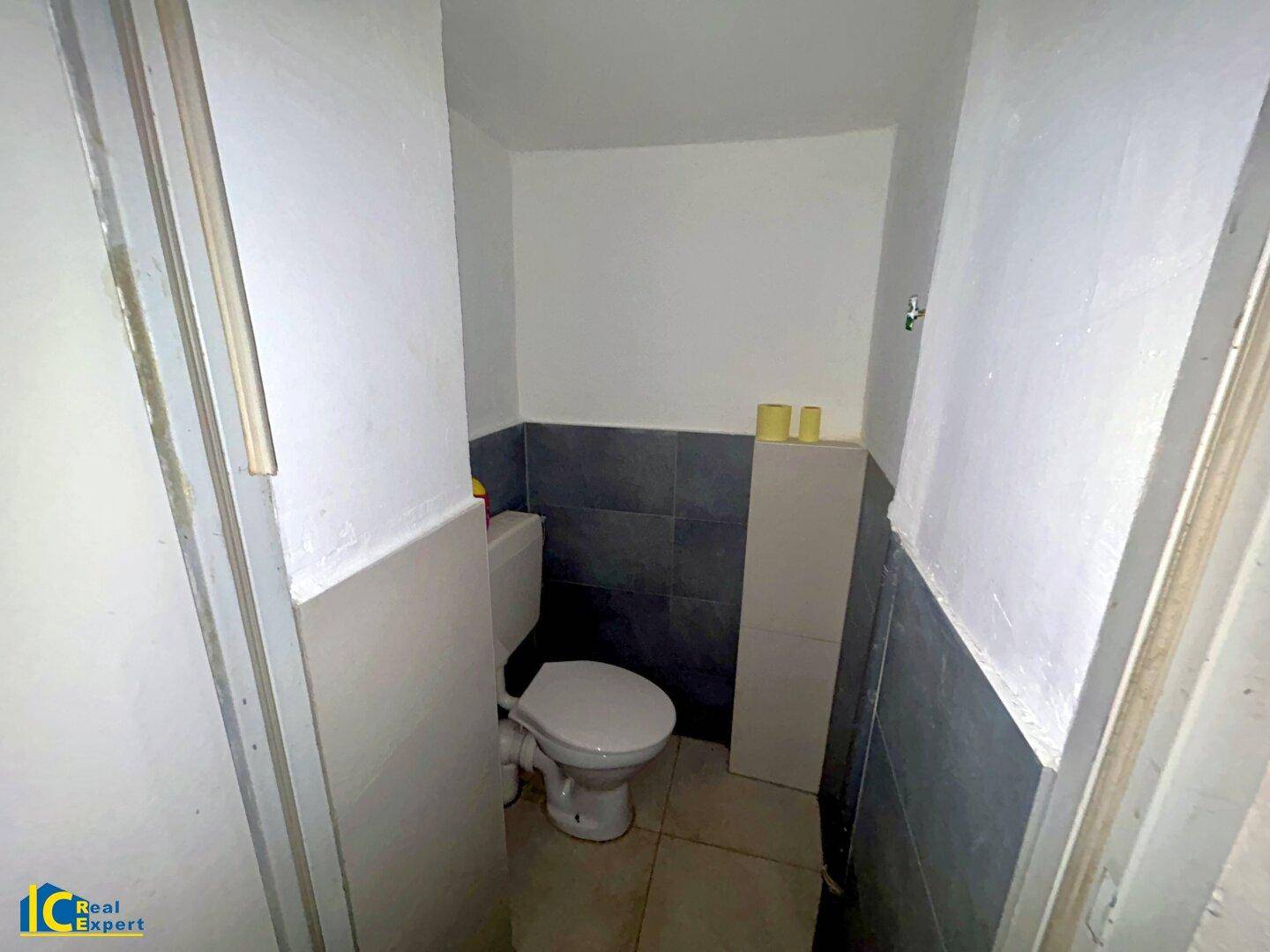 Kleine Toilette mit Fliesen an den Wänden und einem einfachen WC.