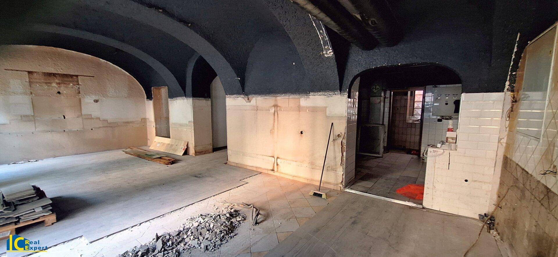 Großer Kellerraum mit dunklen Gewölbedecken und teilweise gefliesten Wänden, bereit zur Renovierung.