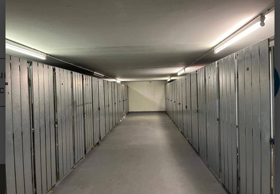 Langer Gang mit zahlreichen individuellen Lagerabteilen in einem Kellerbereich.