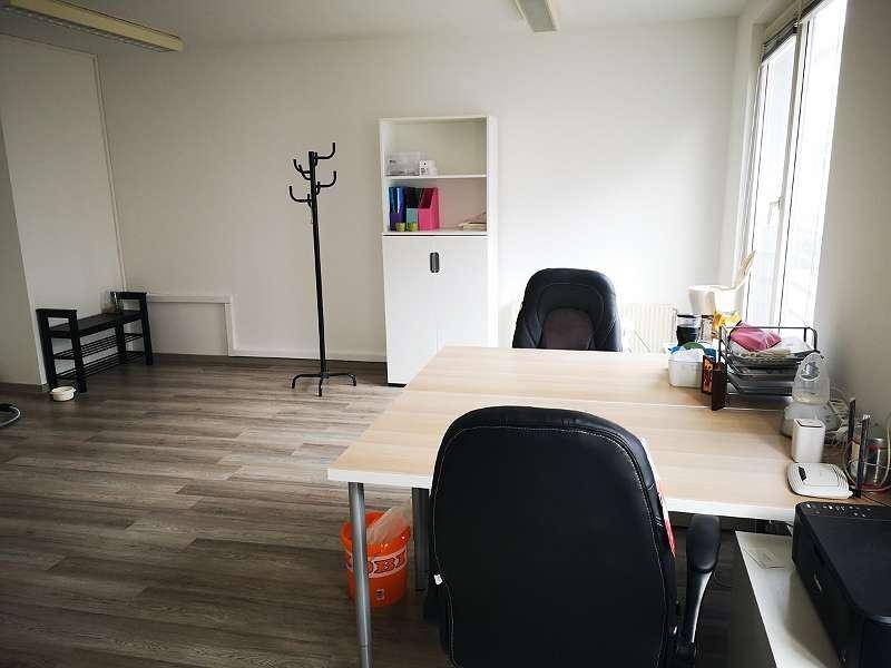 Büroraum mit Laminatboden, einem Schreibtisch und einem Regal an der Wand.