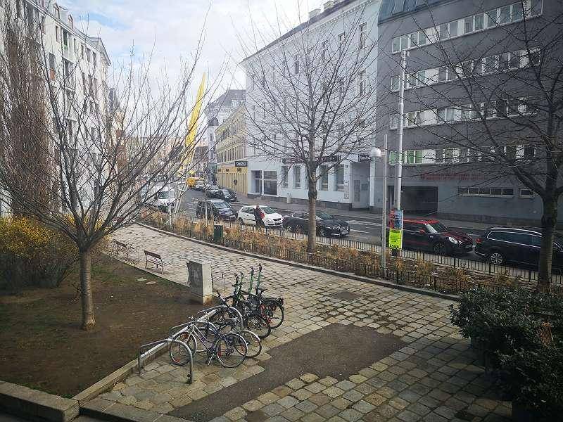 Blick auf eine städtische Straße mit parkenden Autos und Gebäuden.
