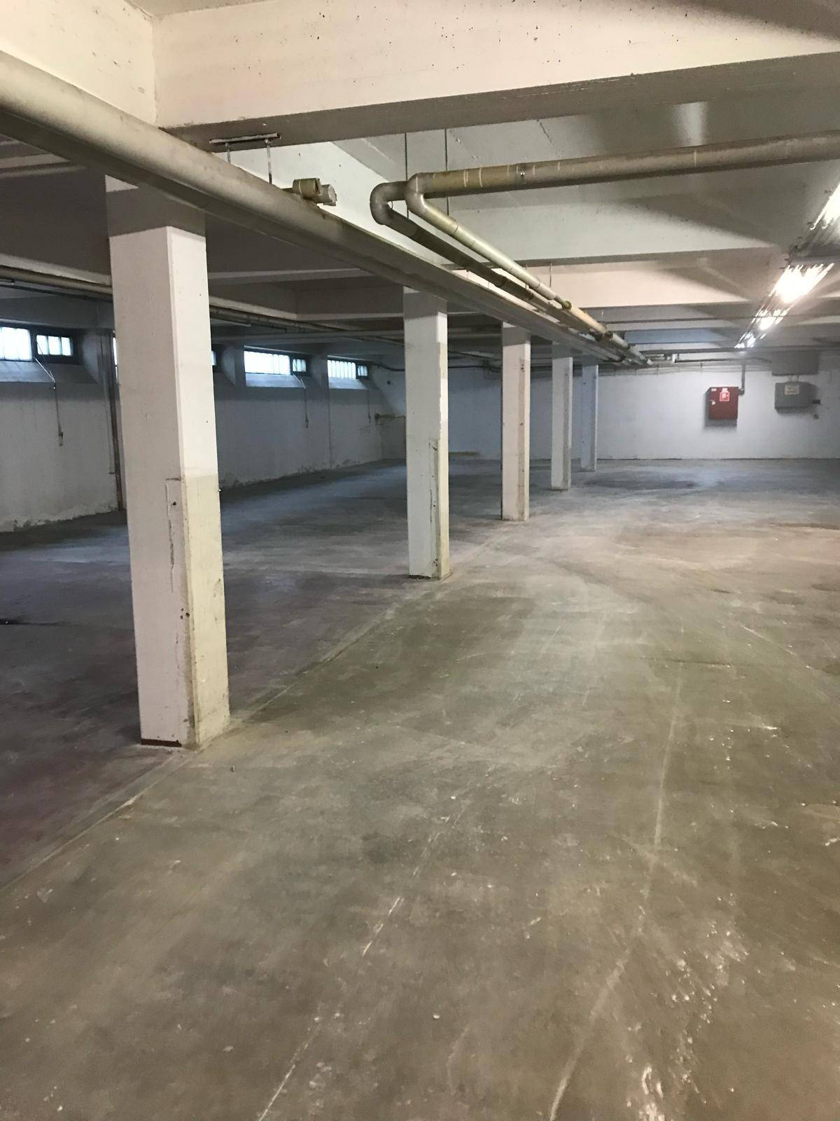 Weitläufiger Kellerbereich mit Betonboden, tragenden Säulen und sichtbaren Installationen an der Decke.