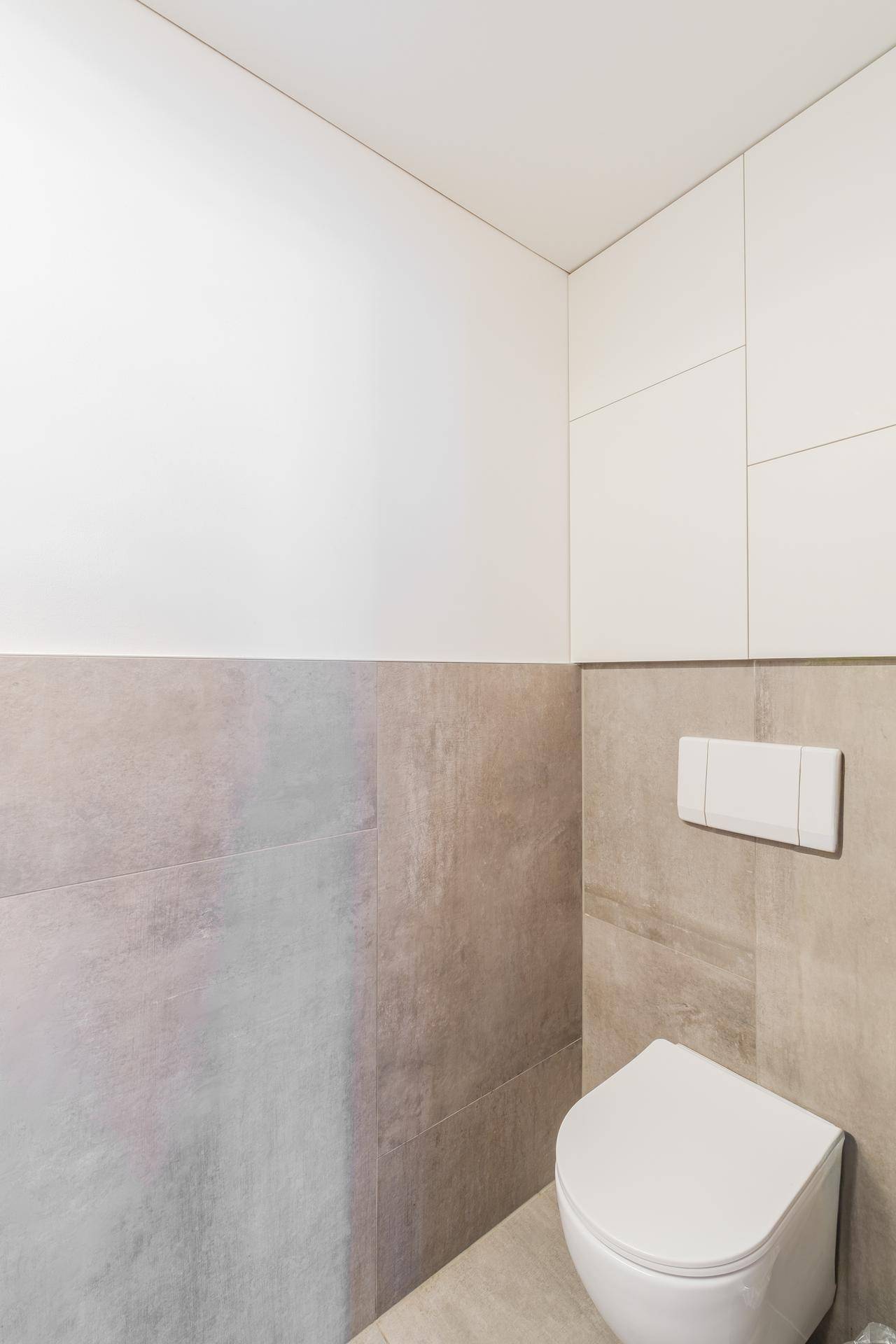 Gäste-WC mit wandhängendem WC und modernen Fliesen in neutralen Farbtönen.