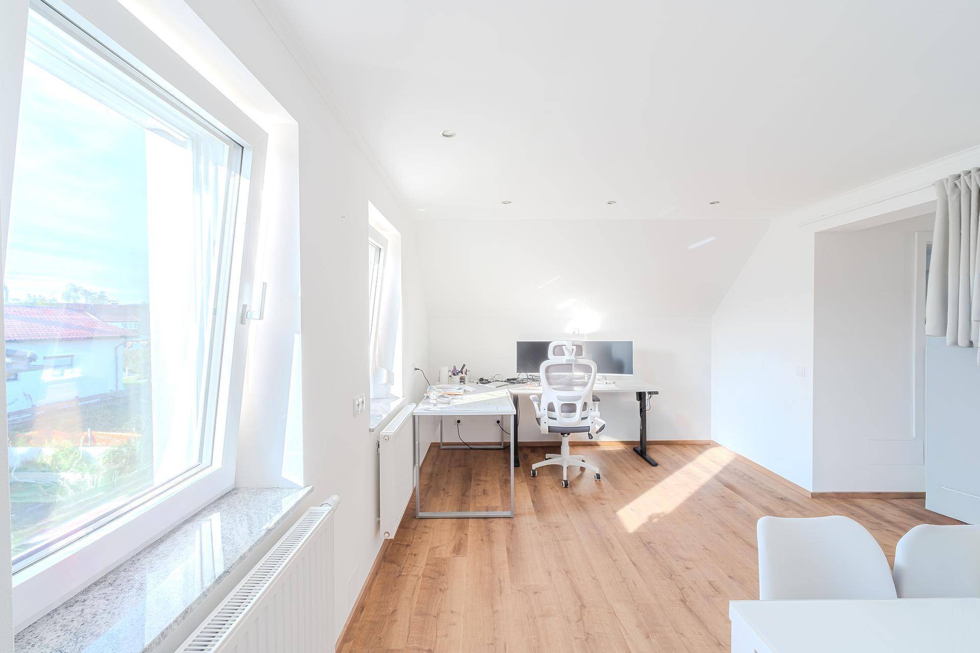 Helles Arbeitszimmer im Dachgeschoss mit Holzboden, Schreibtisch und viel Tageslicht.