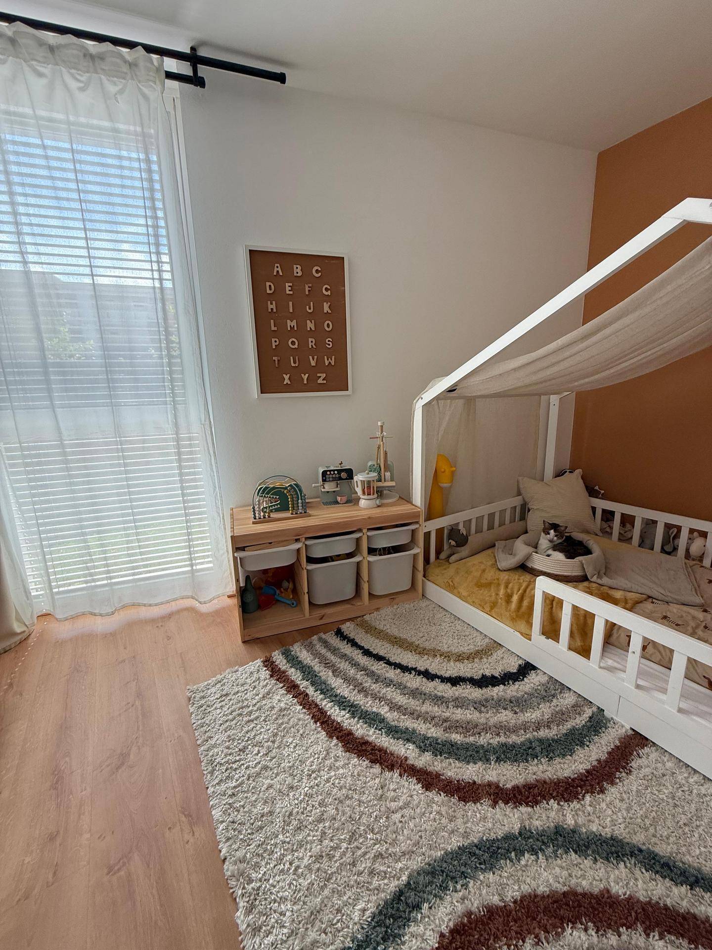 Helles Kinderzimmer mit Himmelbett, Spielbereich und großem Fenster für viel Tageslicht.