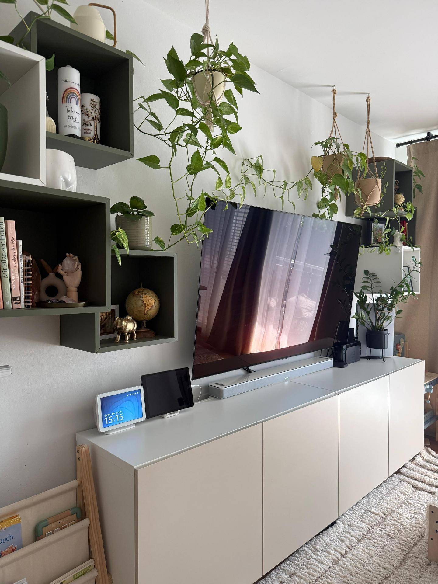 Detailansicht des Wohnzimmers mit Fernseher, schwebenden Regalen und hängenden Pflanzen.