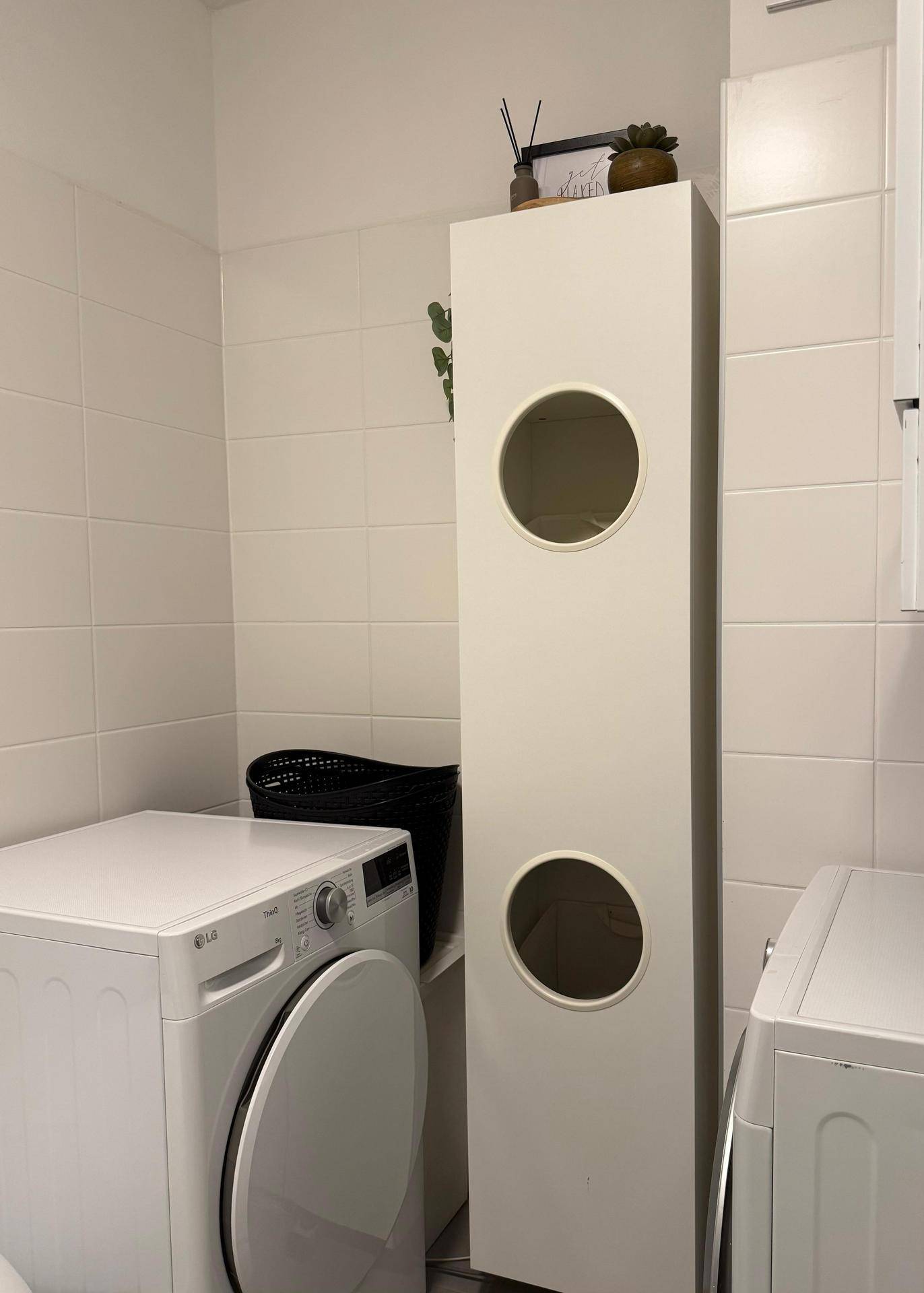 Praktischer Hauswirtschaftsbereich mit Waschmaschine und hohem Stauraumschrank.