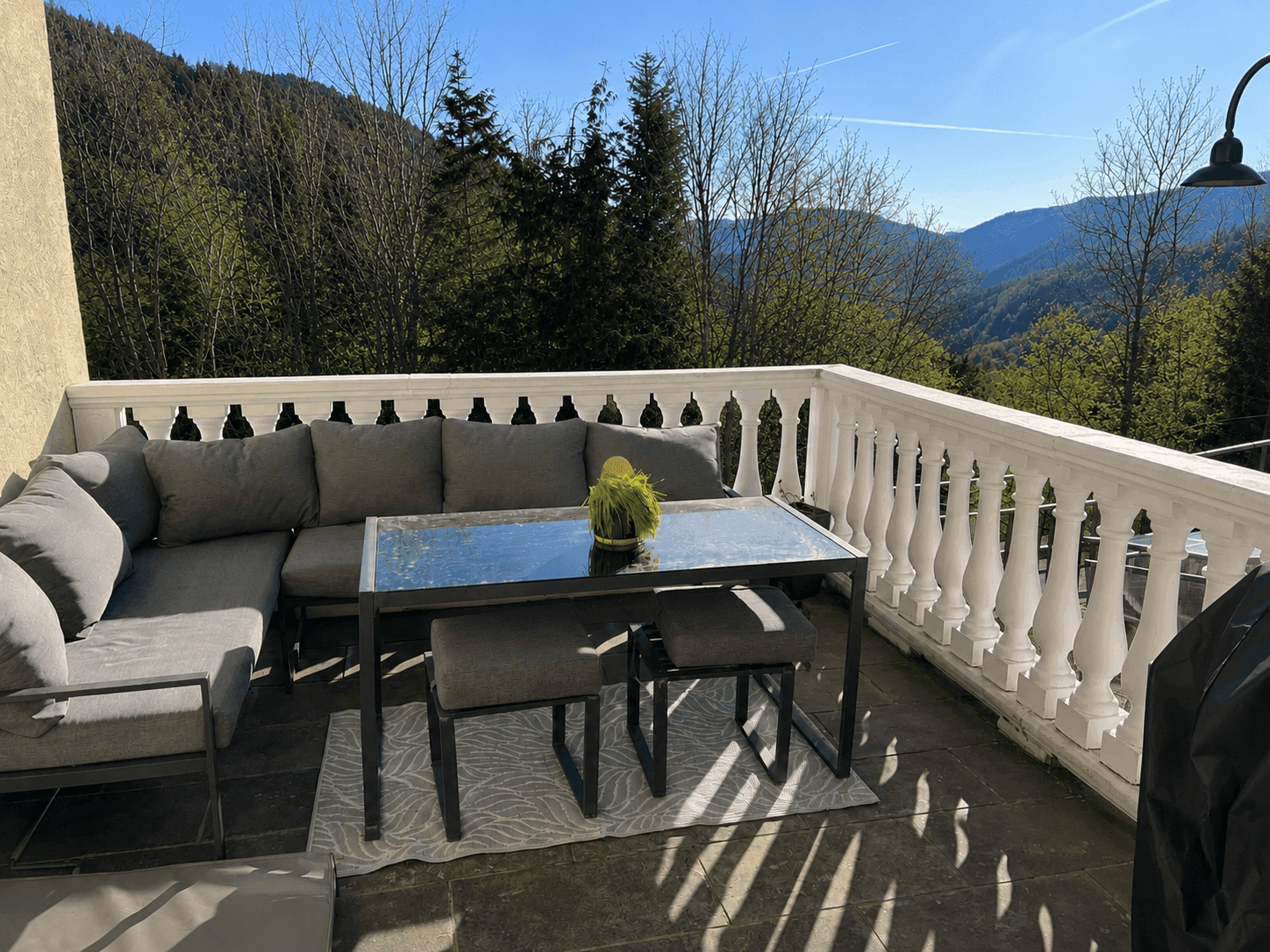 Große Terrasse mit modernen Loungemöbeln und weitem Blick auf die bewaldeten Berge.