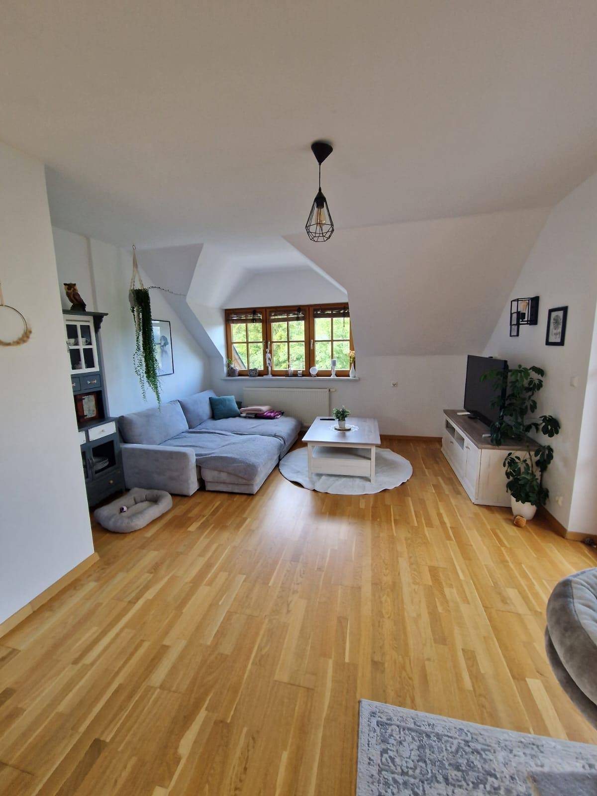 Gemütliches Wohnzimmer im Dachgeschoss mit Sofa, Couchtisch und Holzboden.