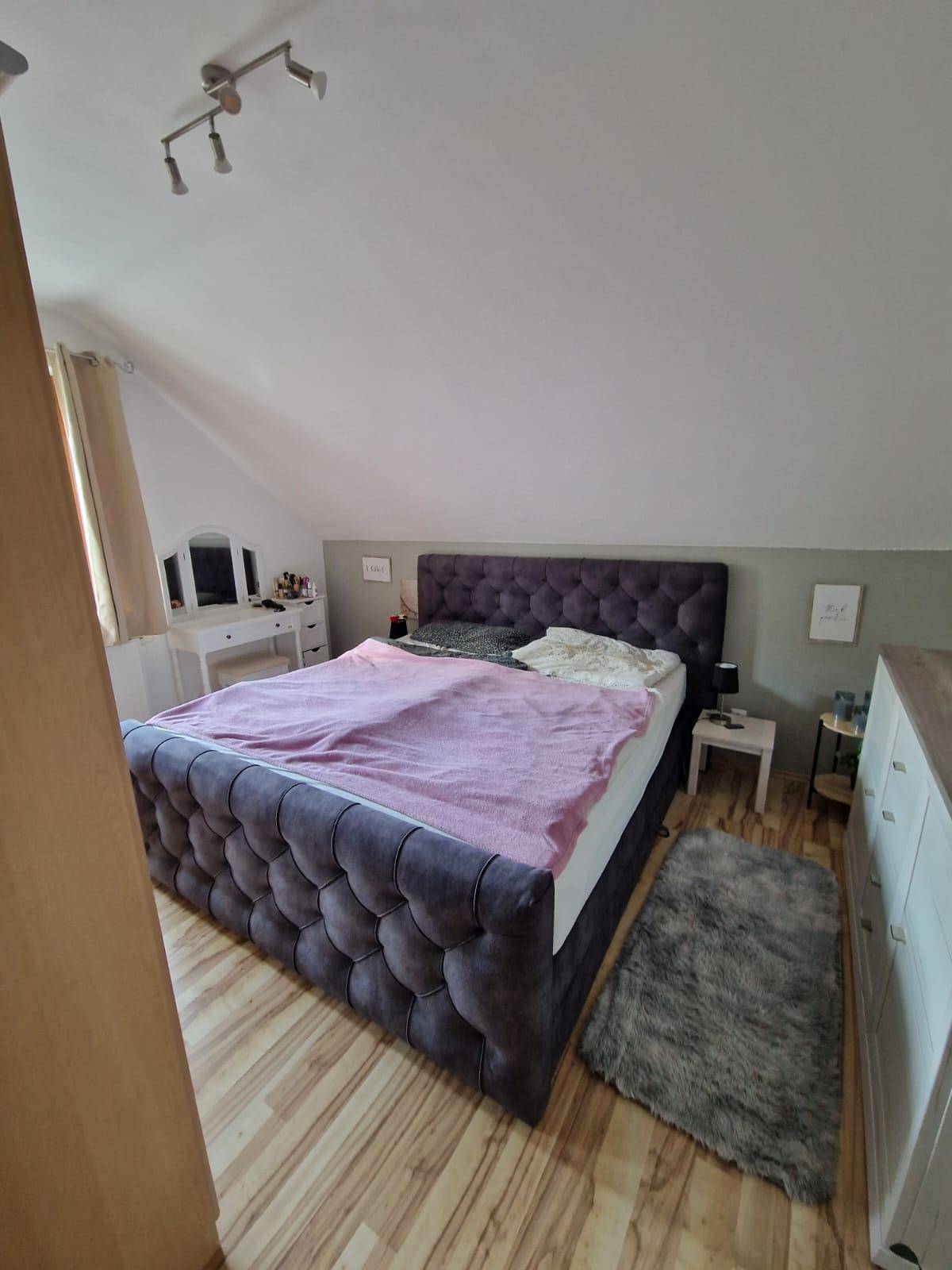 Gemütliches Schlafzimmer im Dachgeschoss mit großem Bett und Dachschräge.