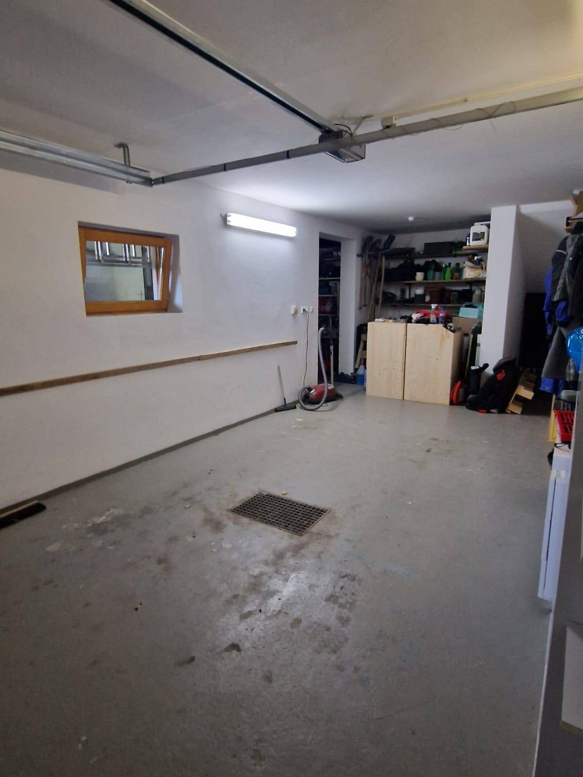 Geräumige Garage mit Fenster, Betonboden und Stauraum.