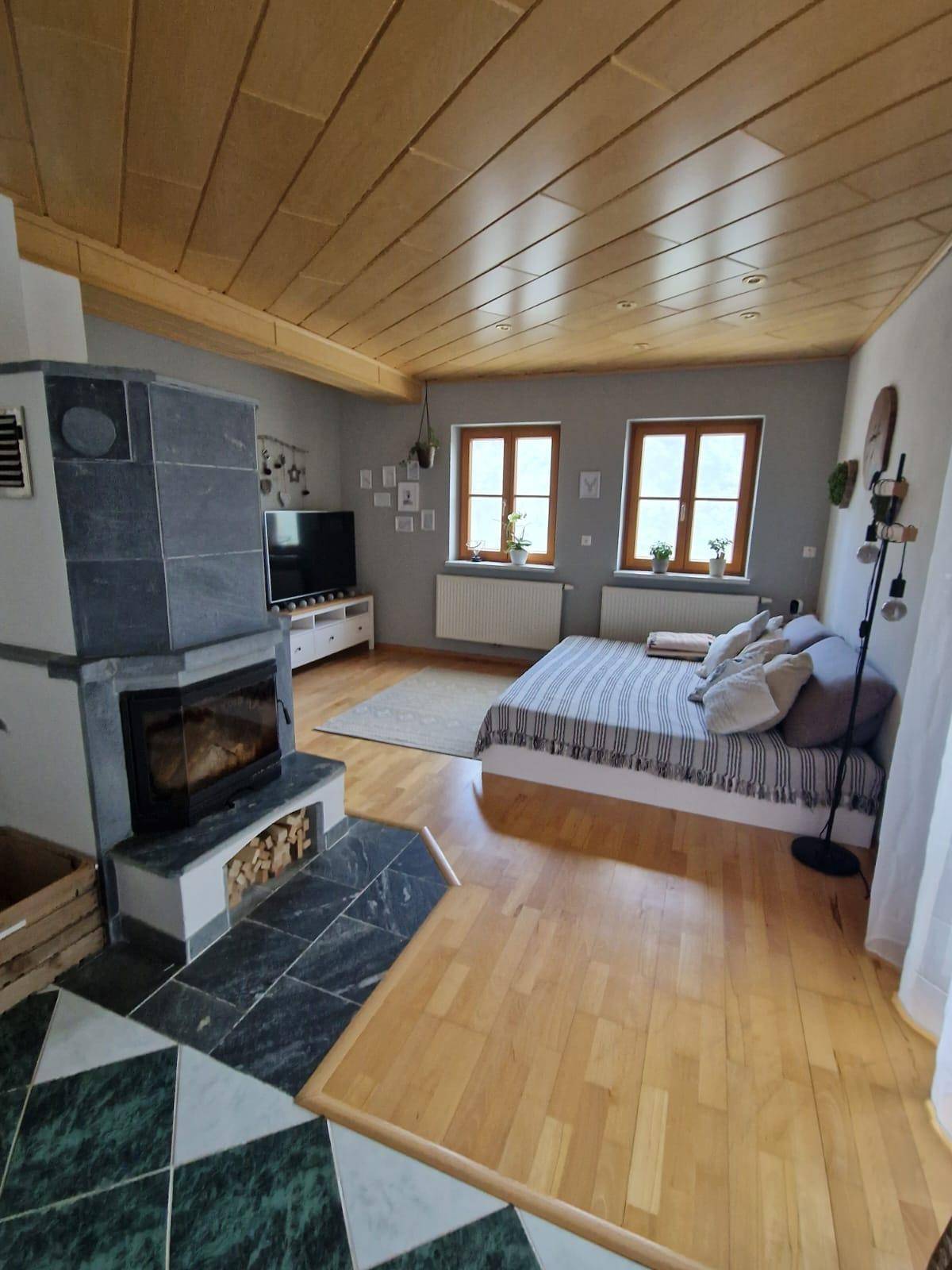 Gemütlicher Wohnbereich mit Kamin, Holzboden und einer Holzdecke, kombiniert mit Schlafbereich.