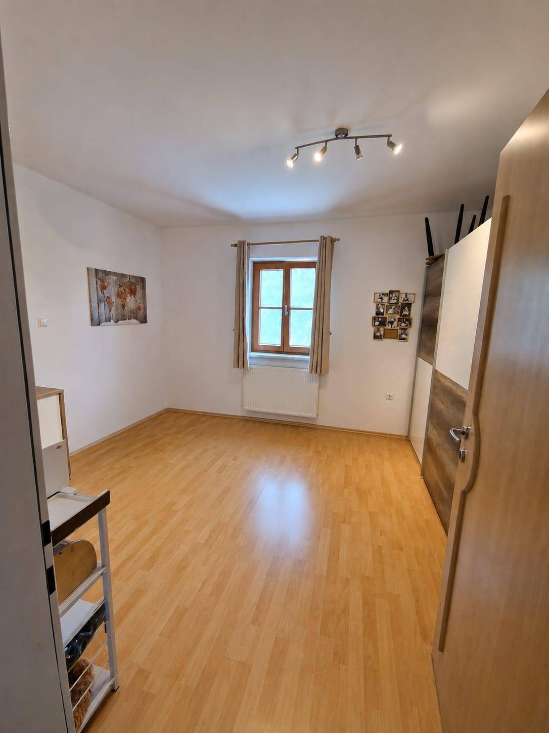 Helles Schlafzimmer mit Holzboden, weiß gestrichenen Wänden und einem Fenster.
