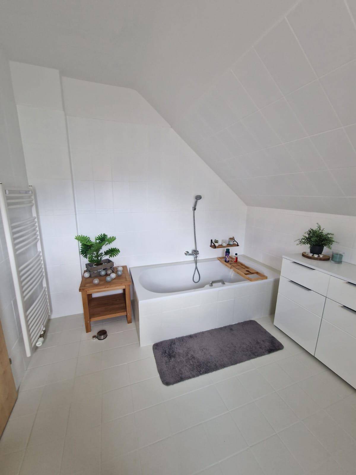 Geräumiges Badezimmer mit Badewanne, Fliesenboden und Dachschräge.